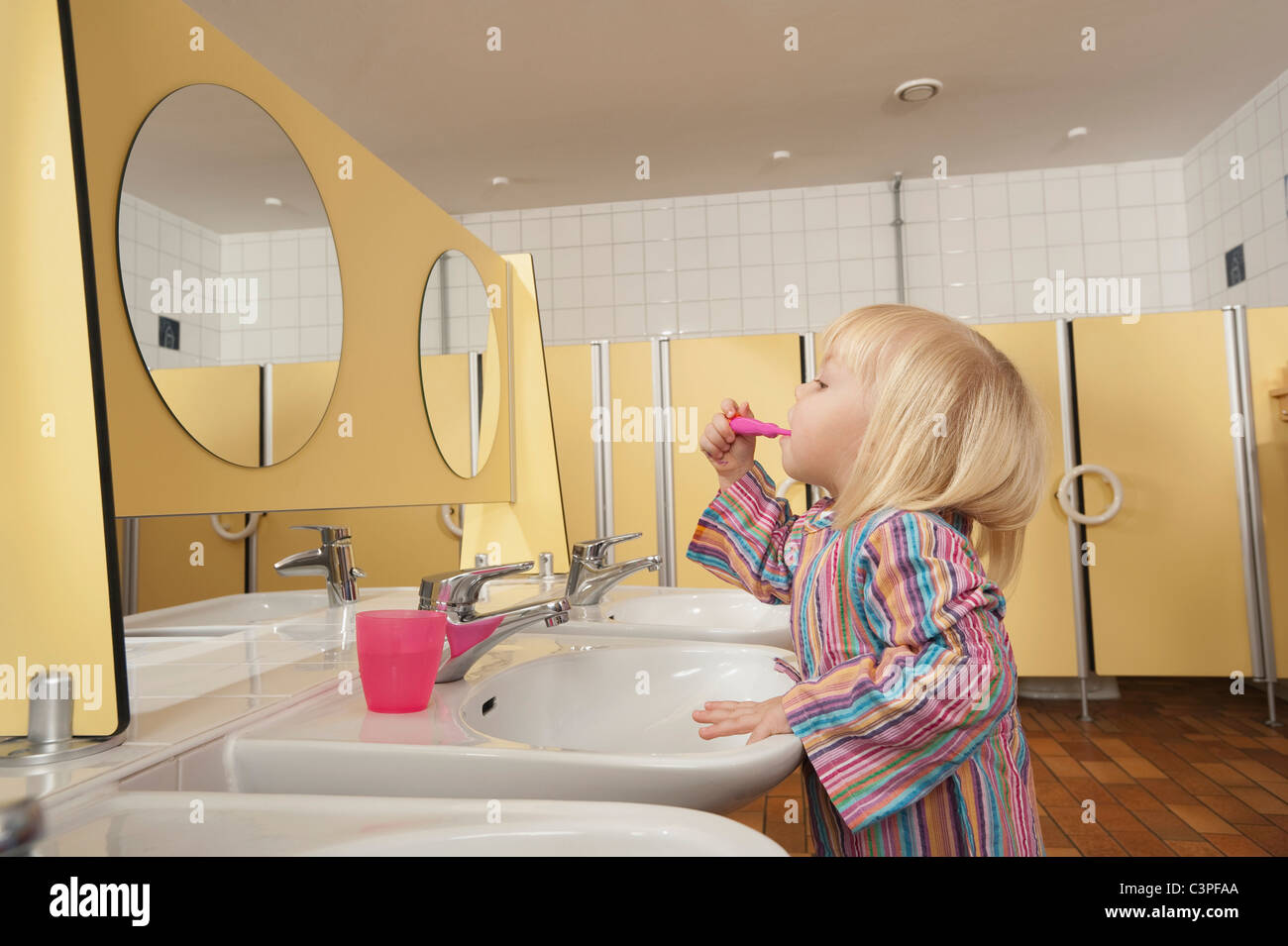 Deutschland, Mädchen (3-4) in Toilette putzen ihre Zähne, Seitenansicht, portrait Stockfoto