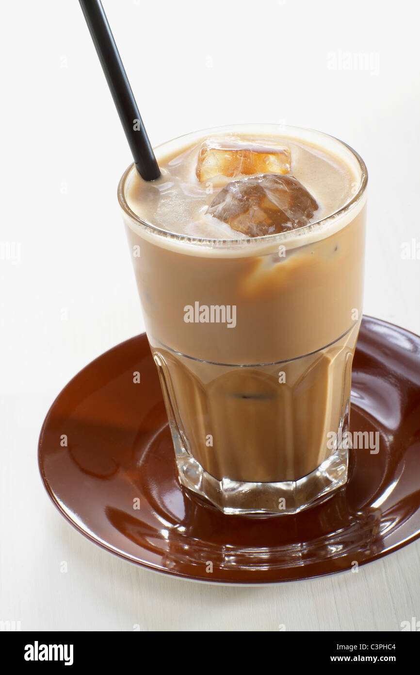 Glas Eiskaffee mit Eiswürfeln auf Platte vor weißem Hintergrund Stockfoto