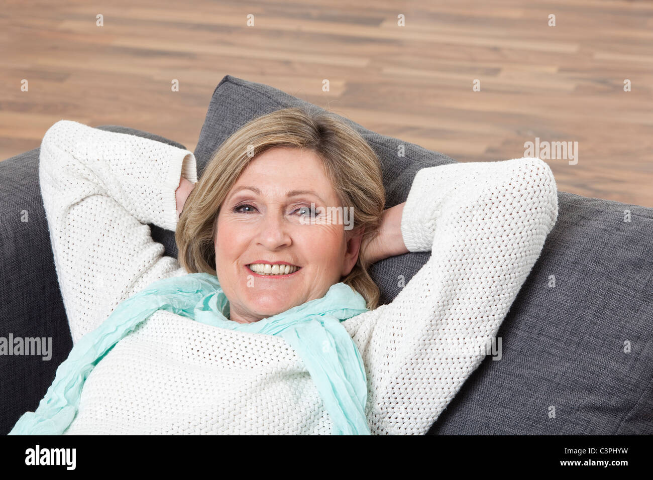 Frau liegend mit dem Kopf in der Hand auf der Couch, Lächeln, Porträt Stockfoto