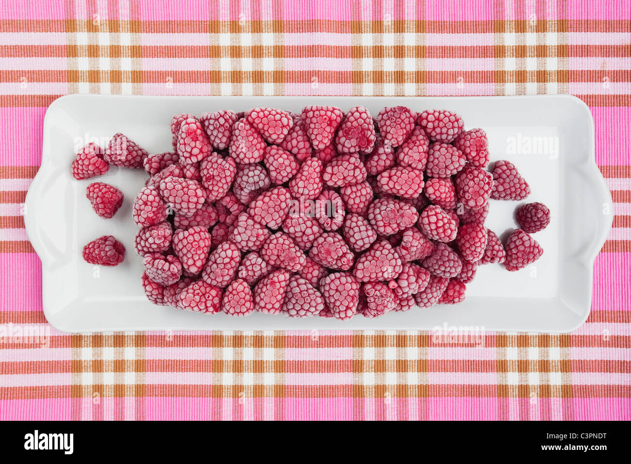 Gefrorene Himbeeren im Tray auf Tischdecke Stockfoto