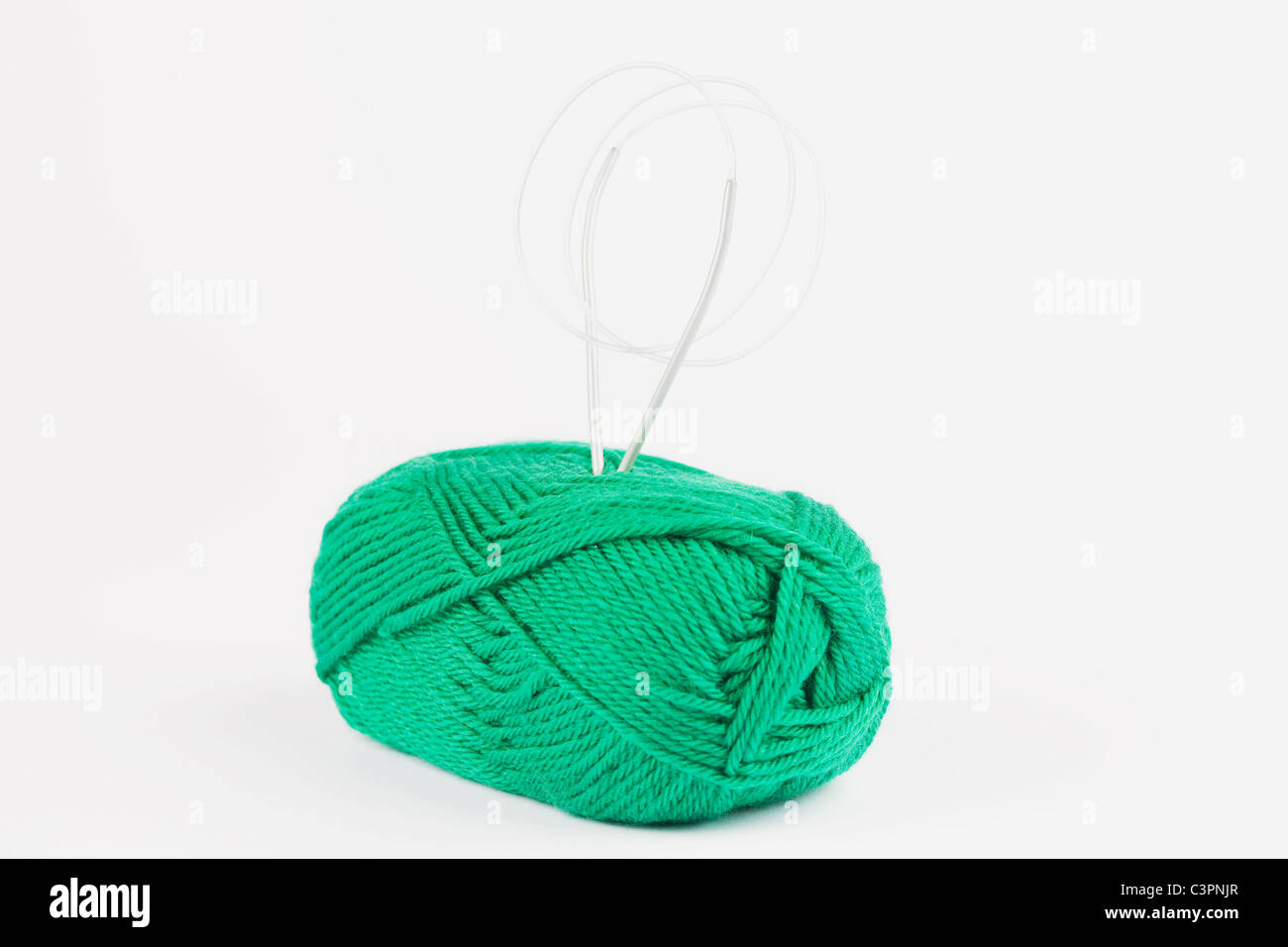 Grüne Wolle und Stricknadeln auf weißem Hintergrund Stockfoto