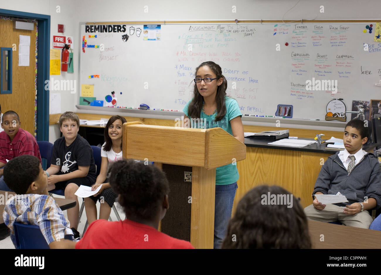 Hispanischen Mädchen in Gläsern spricht vor Studenten beim Mock trial in Mittelschule Sozialkunde Klasse in Pflugerville, TX Stockfoto