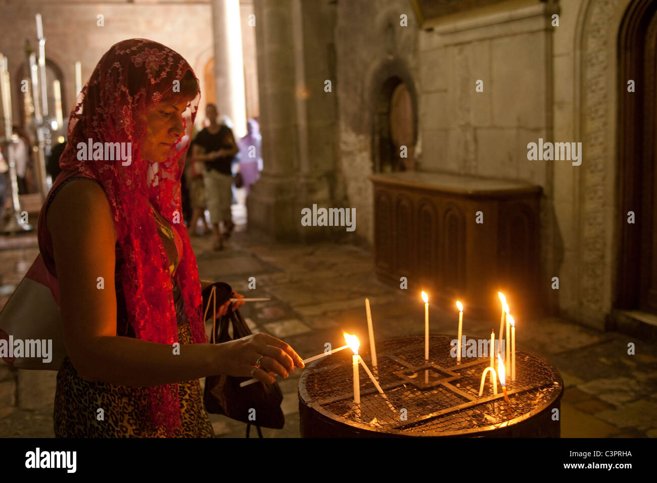 Eine verhüllte Frau zündet eine Kerze in einem Tempel in Jerusalem. Stockfoto