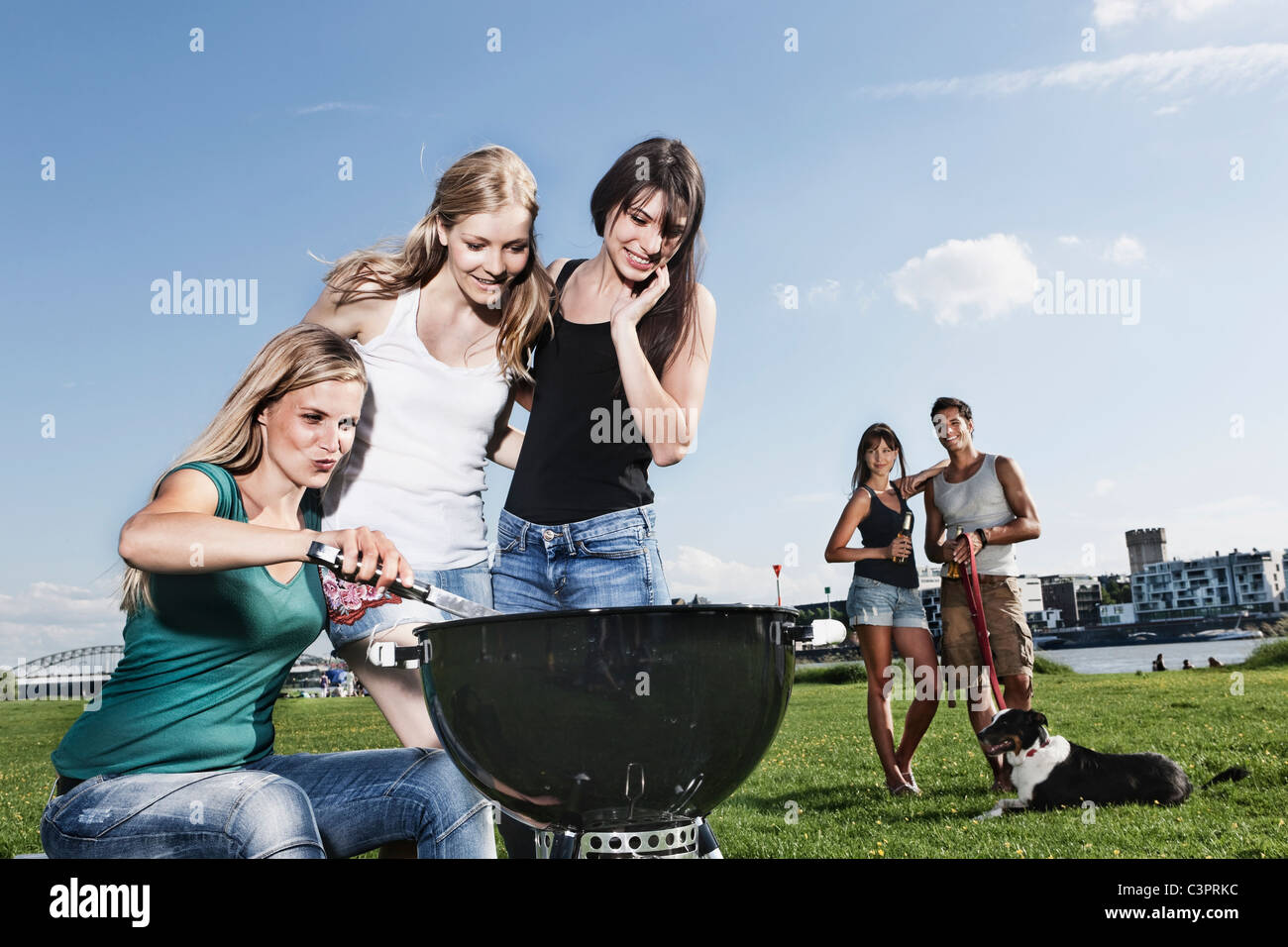 Deutschland, Köln, Frauen Grillen und Freunde im Hintergrund mit Hund Stockfoto