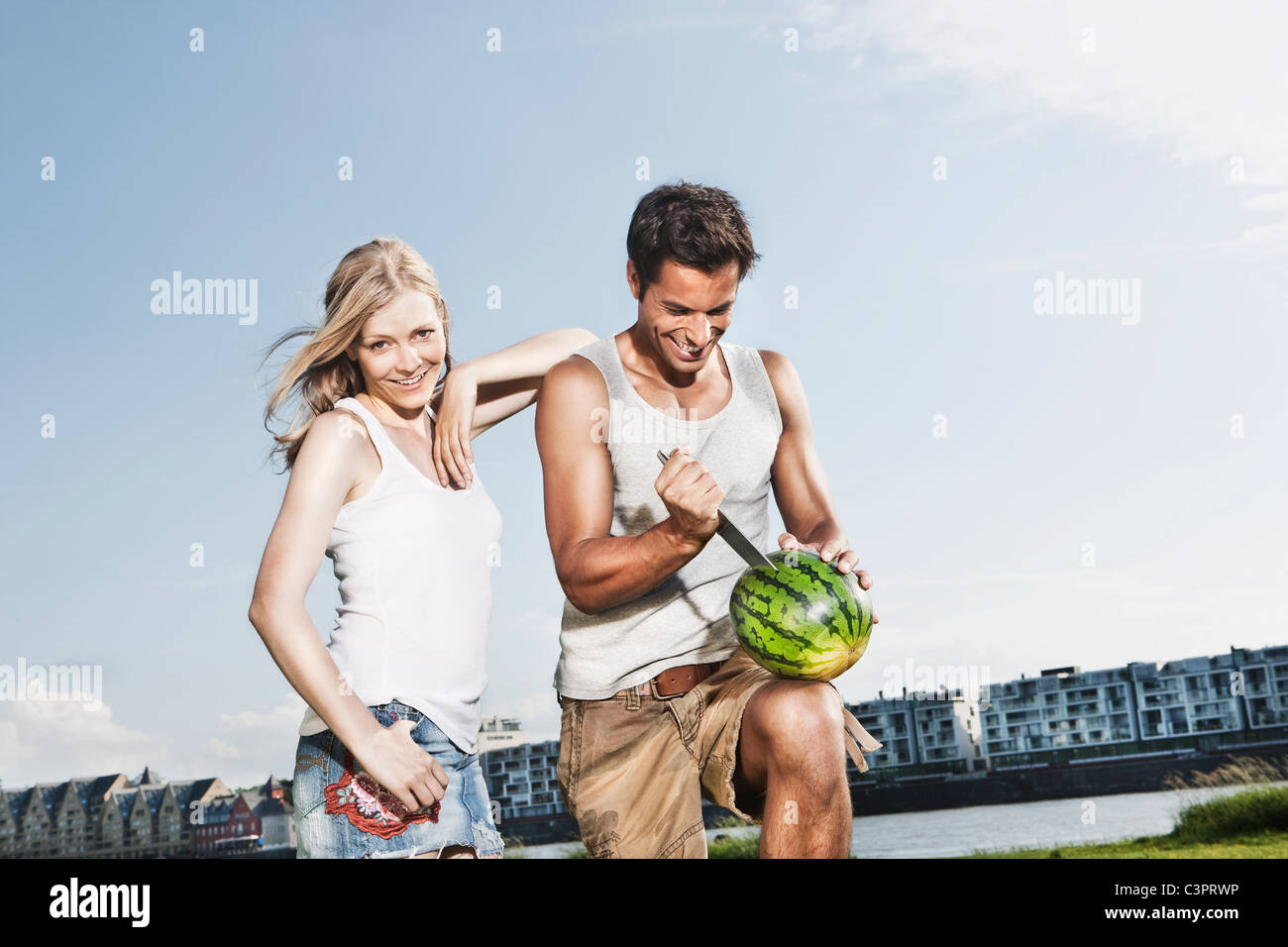 Deutschland, Köln, Mann schneiden Wassermelone, lächelnde Frau Stockfoto