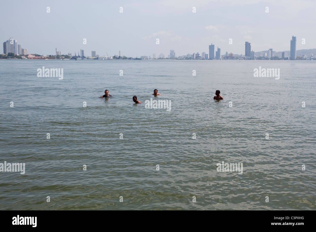 Vier Männer im Meer neben der Stadt.  Kolumbien Stockfoto