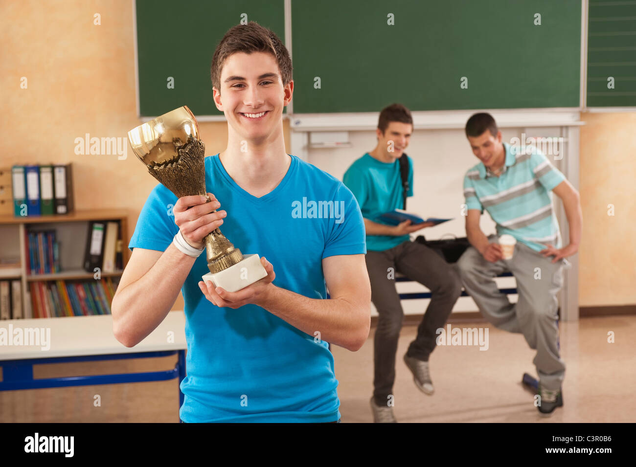 Deutschland, Emmering, jungen Mann, der Trophy zusammen mit Studenten im Hintergrund hält Stockfoto