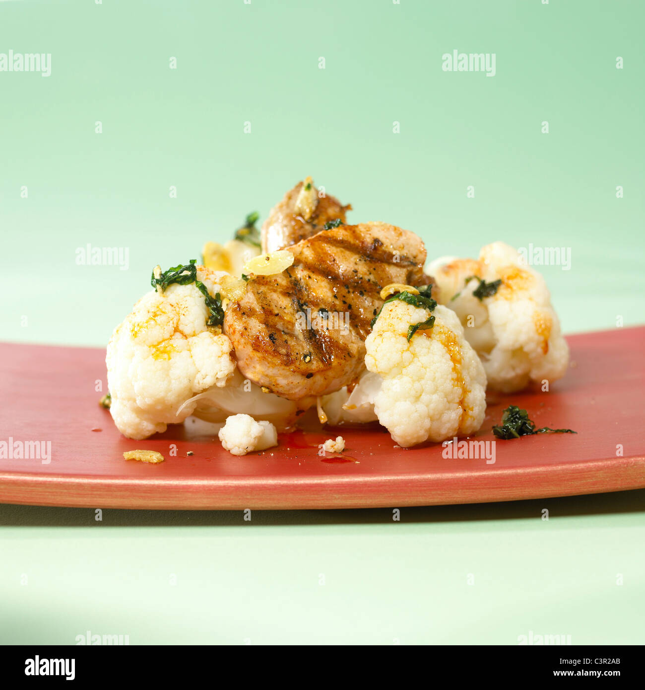 Blumenkohl, garniert mit gebratenem Kalbsfleisch in Platte auf grünem Hintergrund Stockfoto
