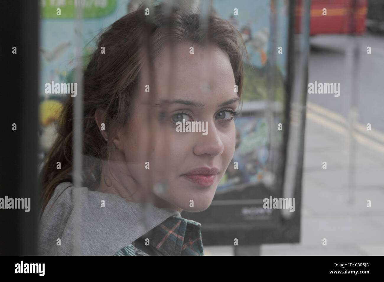 Junge Frau am Bushäuschen in Regen Stockfoto