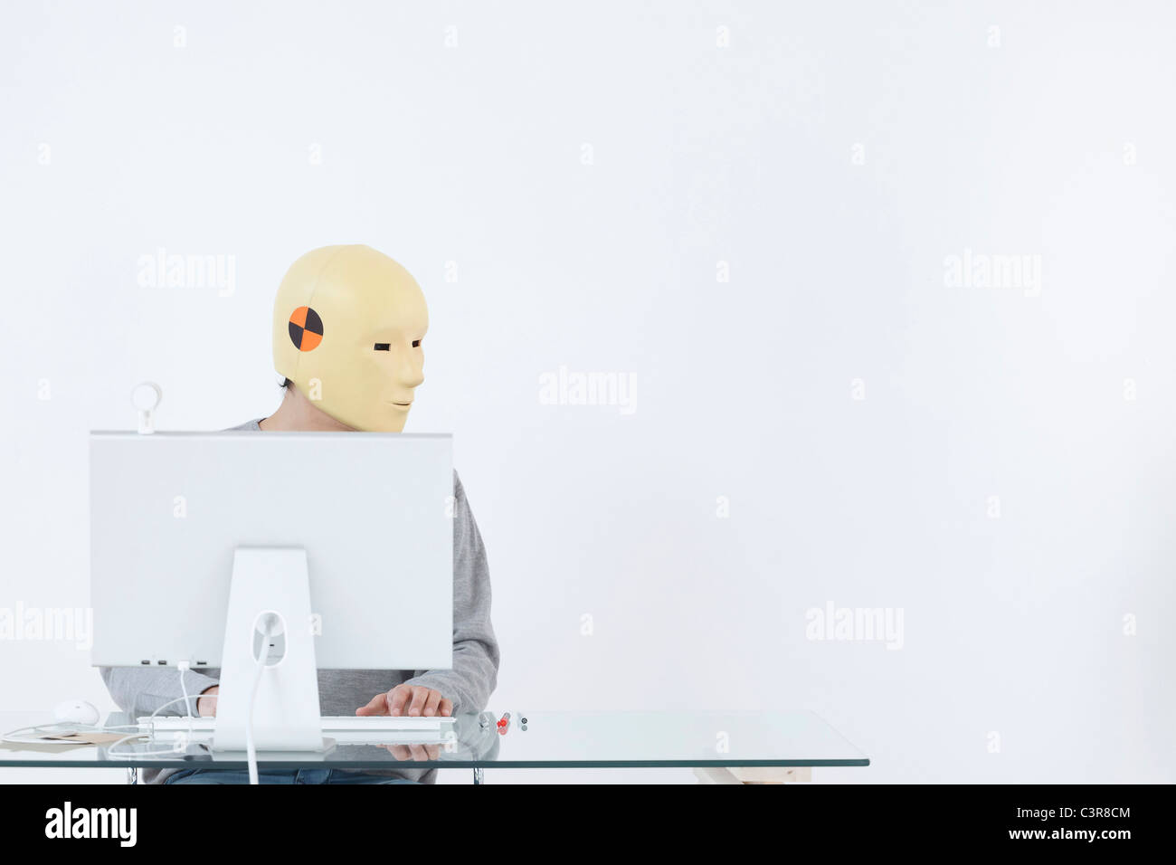Mann mit Absturz Dummy-Maske, die am Computer arbeiten Stockfoto