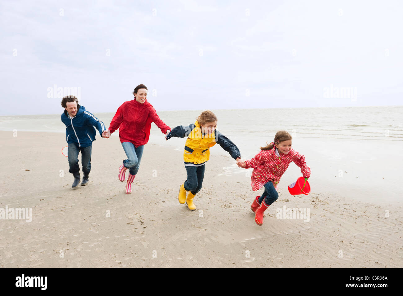 Deutschland, St. Peter-Ording, Nordsee, Familie Hand in Hand und laufen am Strand Stockfoto