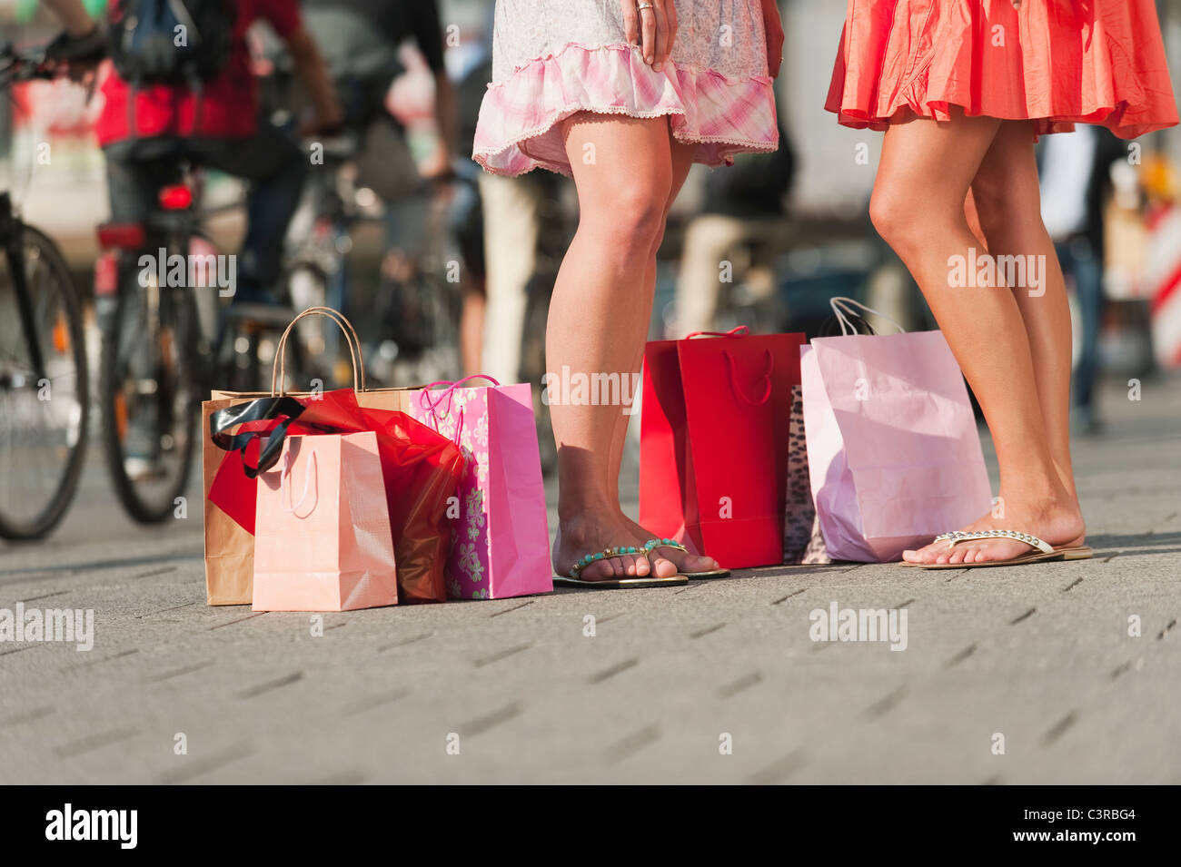 Deutschland, München, Karlsplatz, junge Frauen warten auf Fußweg mit Einkaufstüten Stockfoto