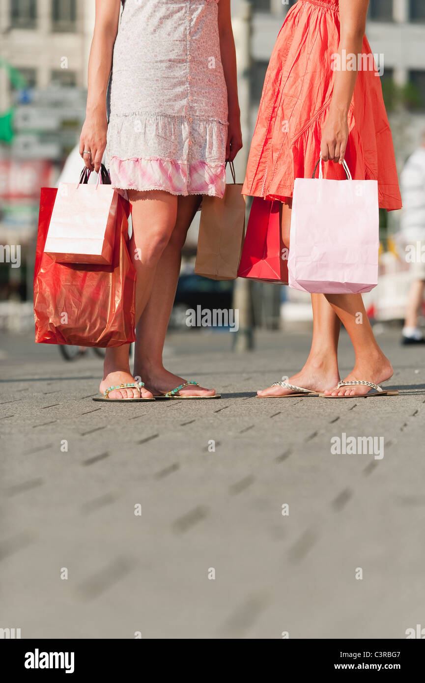 Deutschland, München, Karlsplatz, junge Frauen warten auf Fußweg mit Einkaufstüten Stockfoto