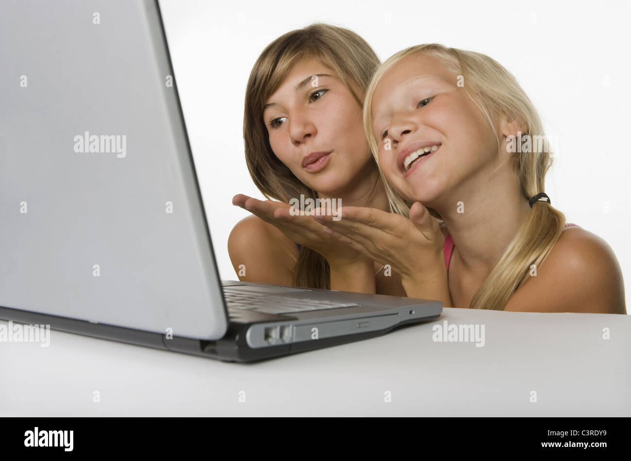 Zwei Mädchen (10-11) mit Blick auf Laptop und weht einen Kuss Stockfoto