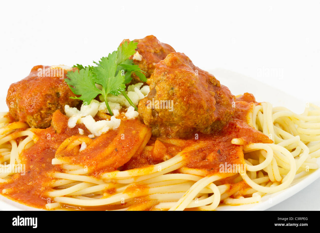 Nahaufnahme von Frikadellen in roter marinara Sauce über Spaghetti und garniert mit Koriander Zweige und Bits von Romano Käse. Stockfoto