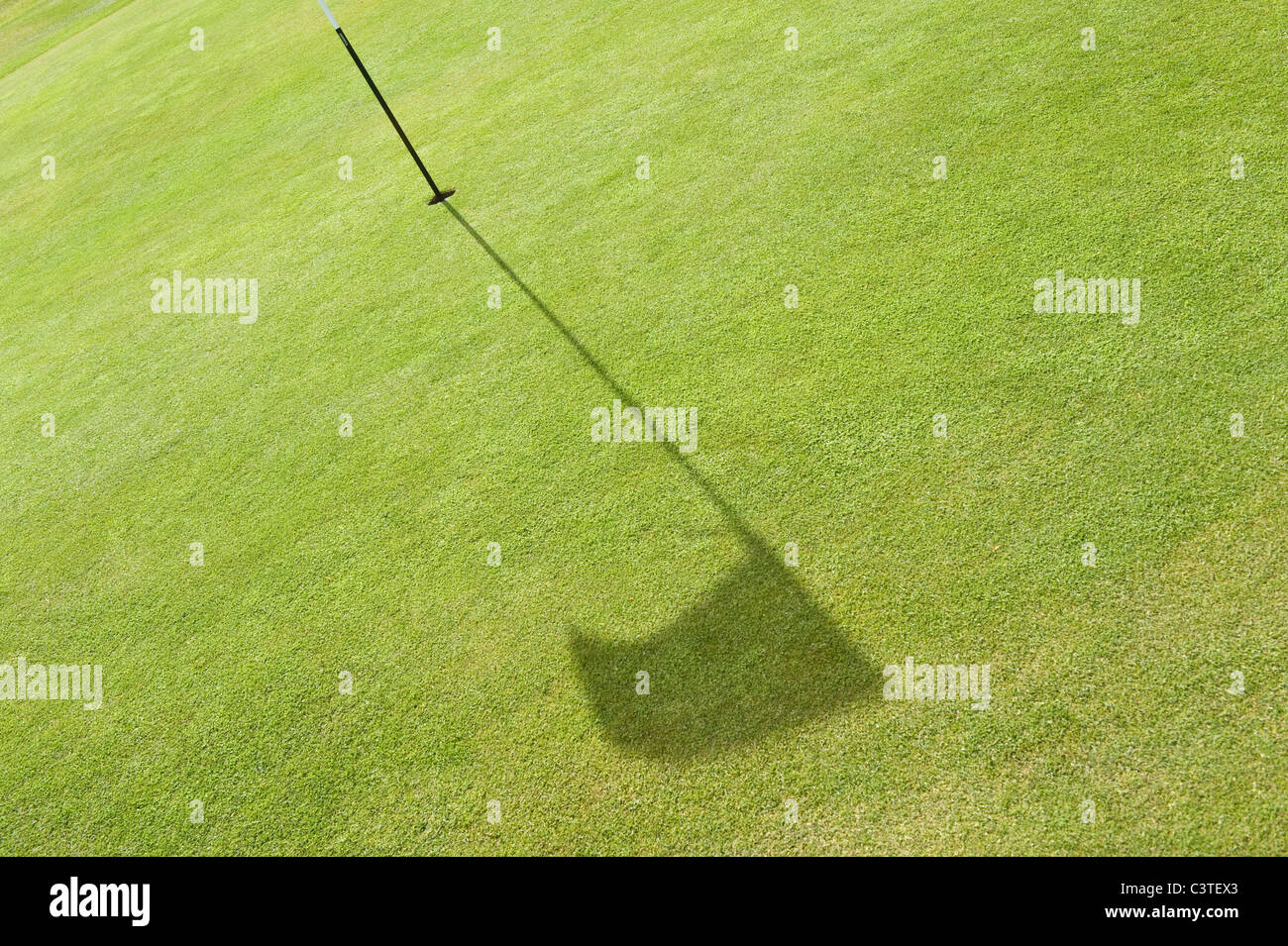 Der Schatten einer Fahne auf dem Grün eines Golfplatzes. Stockfoto