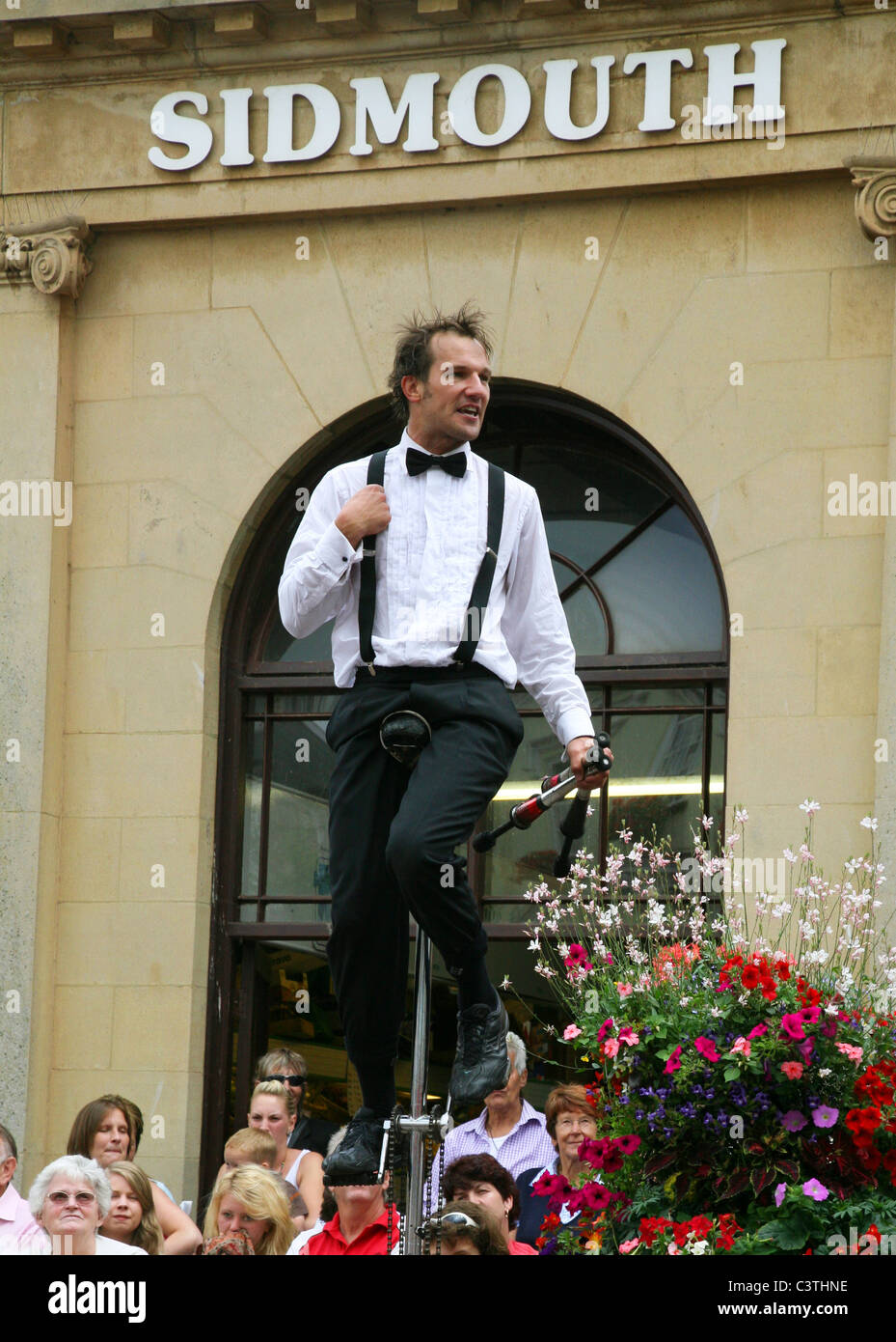 Stelzenläufer Fahrrad Performer zieht eine Menge Sidmouth jährlichen Folk Week Stockfoto