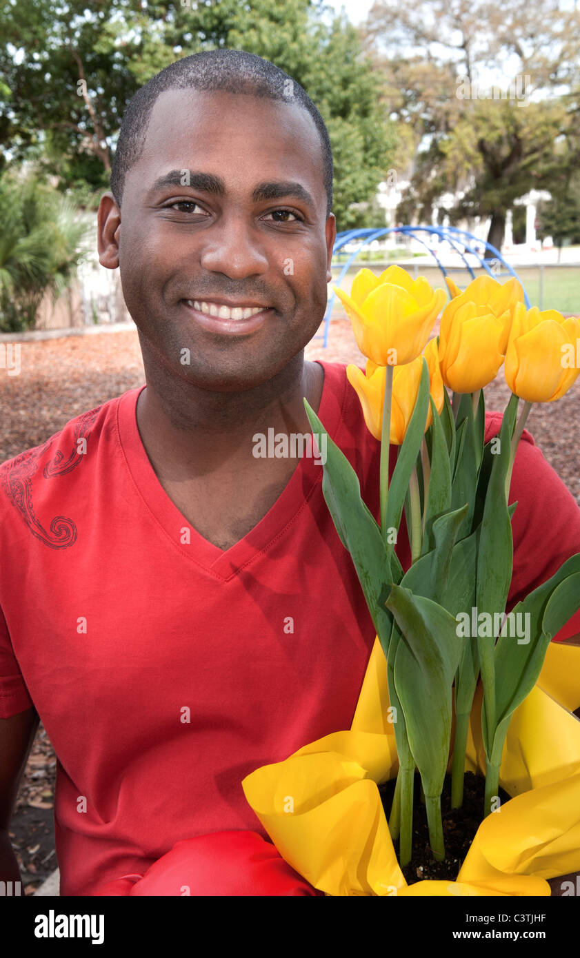 Porträt von schwarzer Mann im Alter von 30 s mit sanften Seite Tulpe Blumen im Freien halten Stockfoto