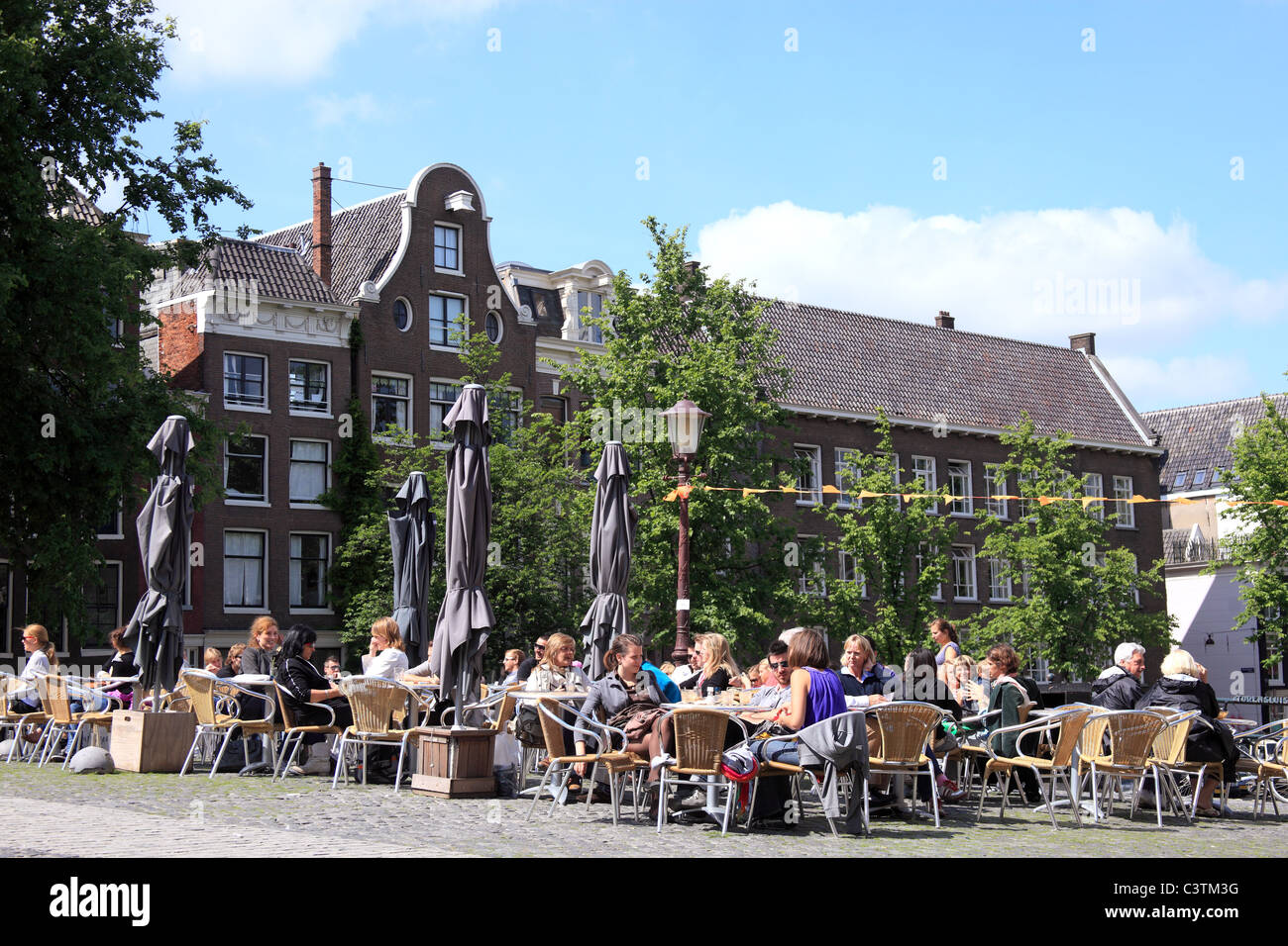 Touristen, die Getränke auf einer Brücke im historischen Viertel von Amsterdam, Holland Stockfoto