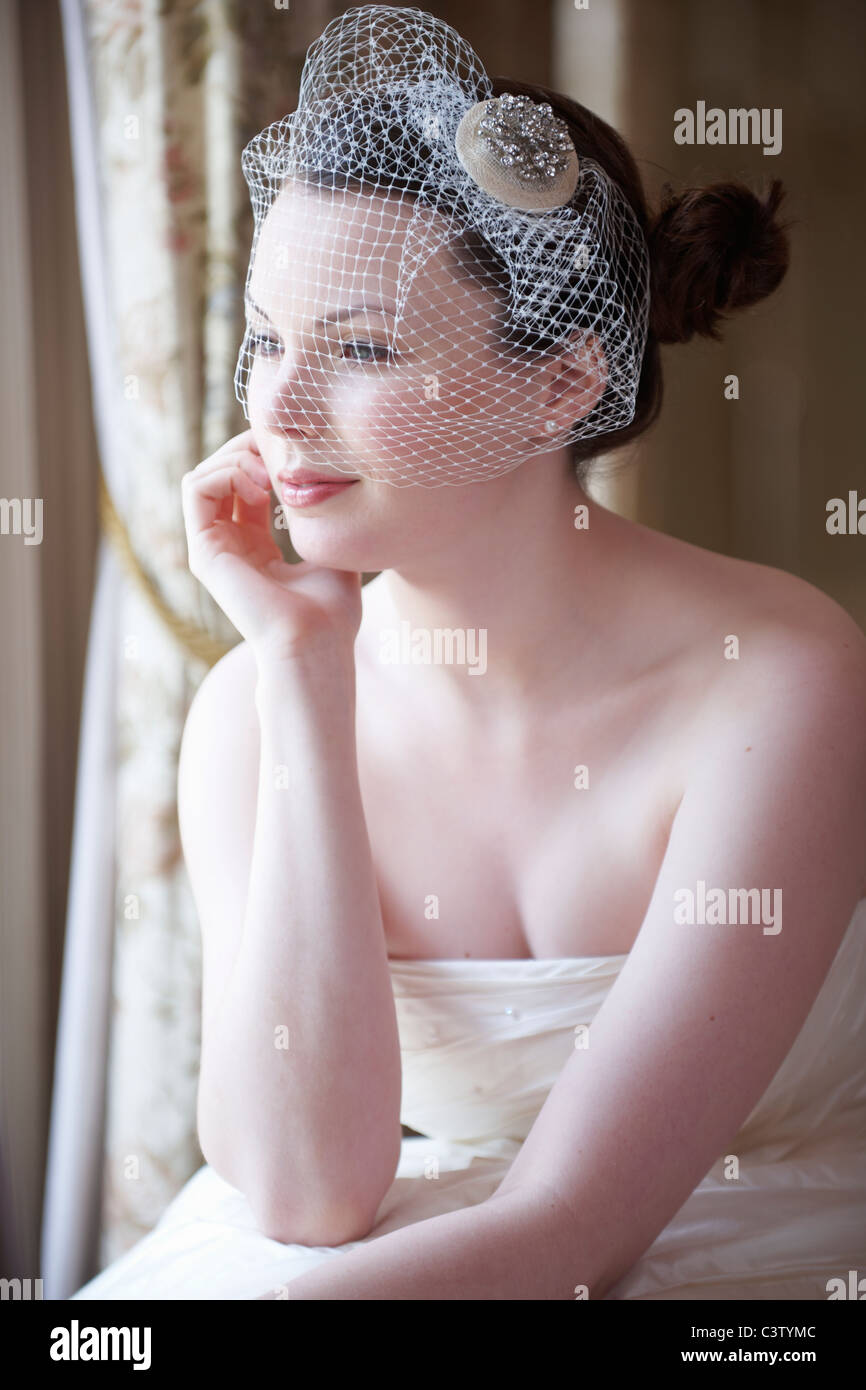 Hübsche Braut Blick aus Fenster und lächelnd am Tag ihrer Hochzeit Stockfoto