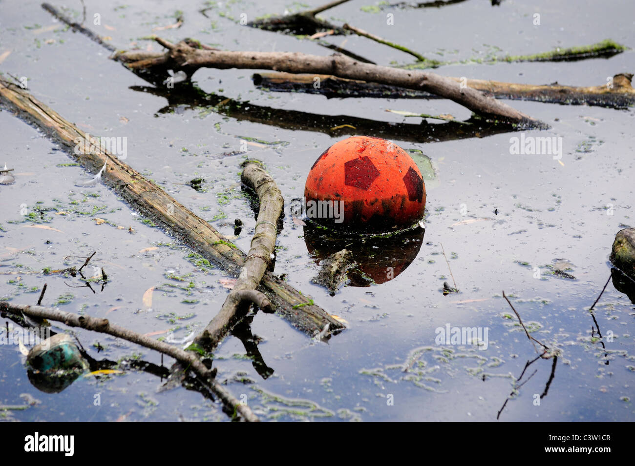 Orange Fußball schwebend in einem Park See England uk Stockfoto