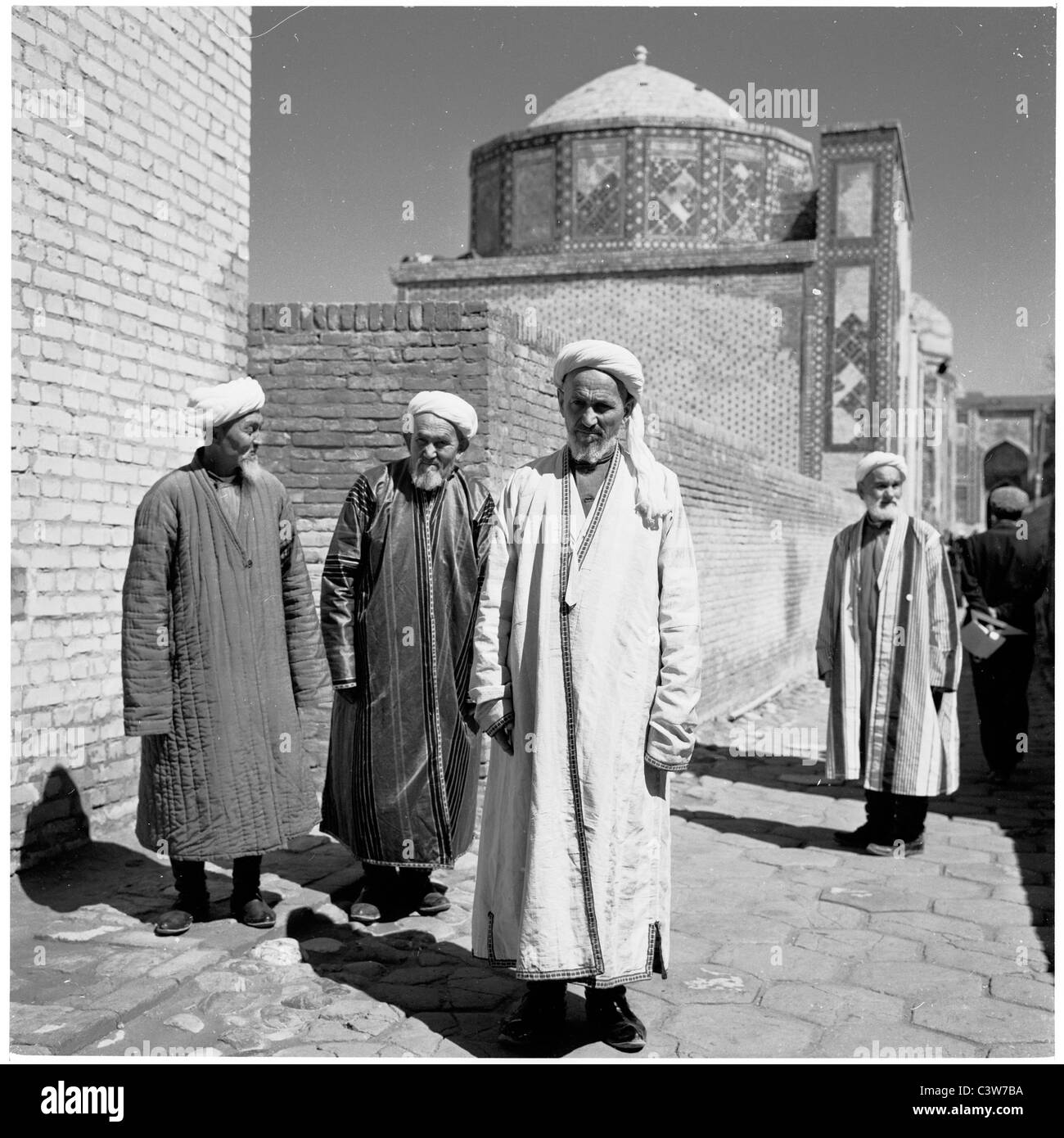 der 1950er Jahre ein Geschichtsbild der drei älteren usbekische Männer in traditionellen langen Gewändern vor den Mauern einer Moschee, Samarkand. Stockfoto