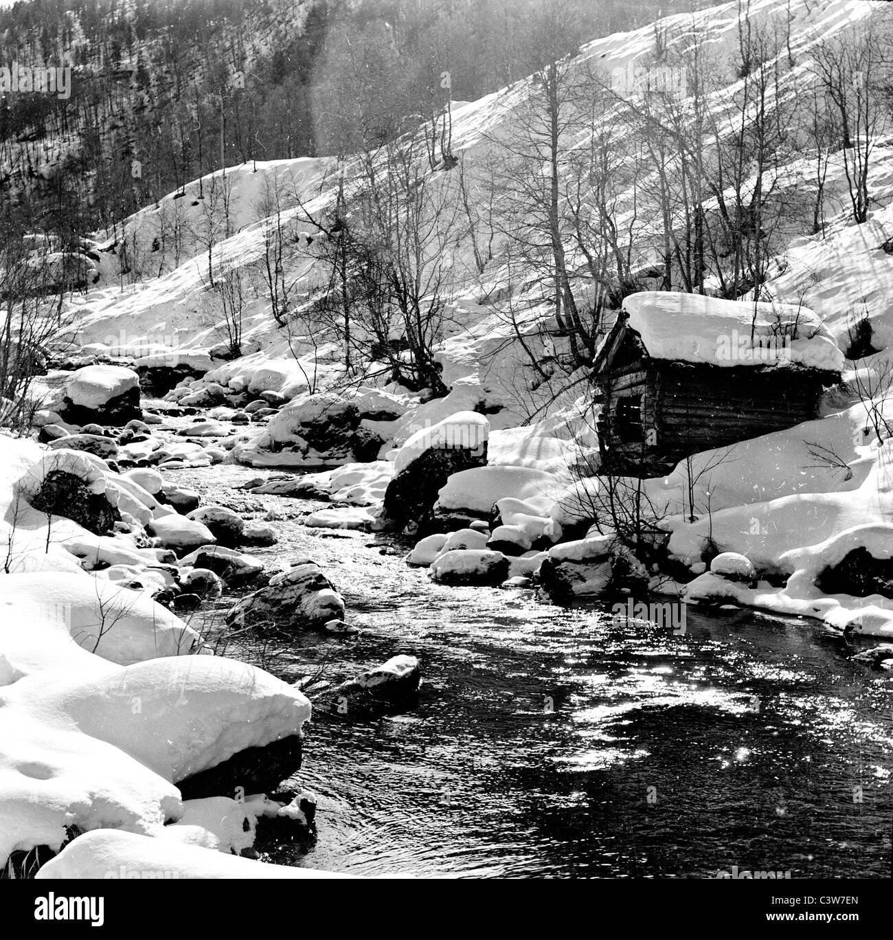 1950er Jahre historische Bild zeigt Winterzeit in Stalheim als Stream fließt tief verschneiten Berg neben einer kleinen Hütte hinunter. Stockfoto