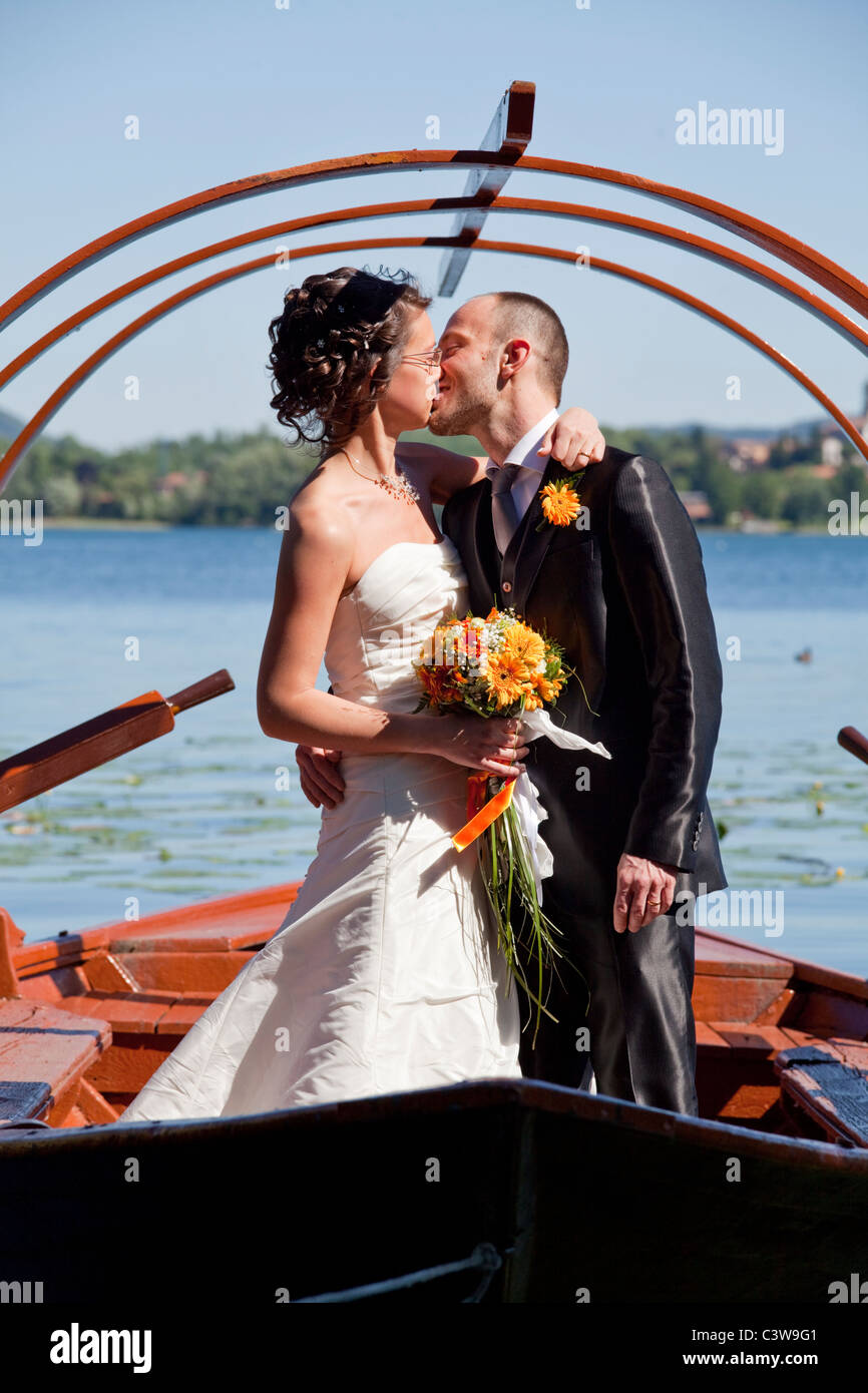 Braut und Bräutigam küssen einander auf einem antiken Boot mitten auf der See Como, Italien Stockfoto