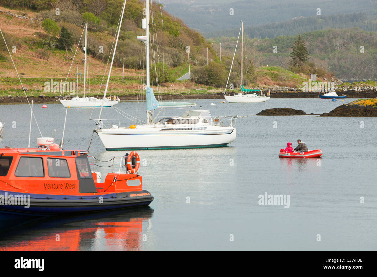 Ein Segler-Zeilen auf seiner Yacht vor Anker im Hafen von Tayvallich auf Loch Sween in der Nähe von Lochgilphead in Schottland, Großbritannien. Stockfoto