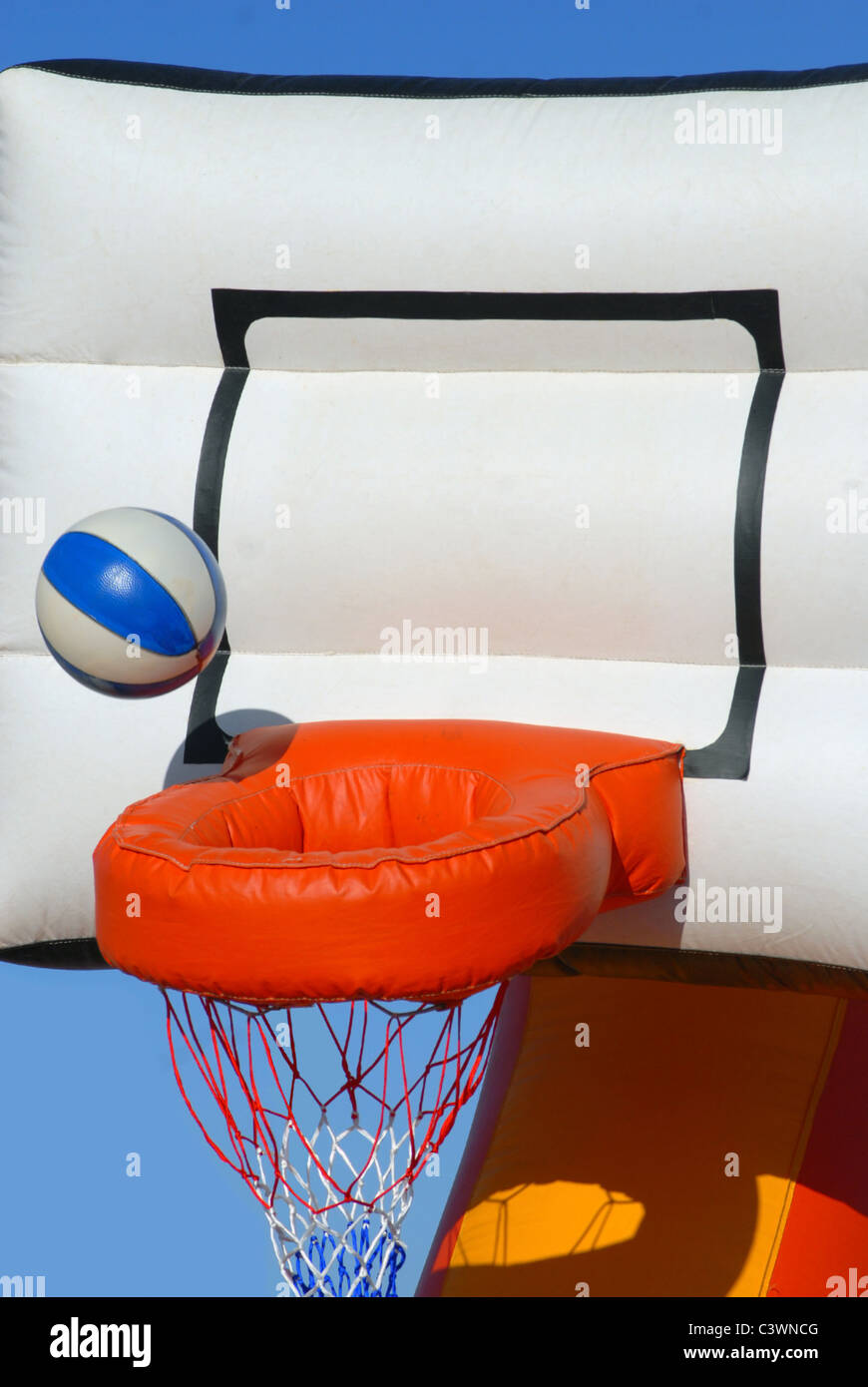 Ball in den Korb zu bekommen. Teilansicht eines bunten aufblasbaren Basketball-Spielzeugs auf blauen Himmelshintergrund Stockfoto