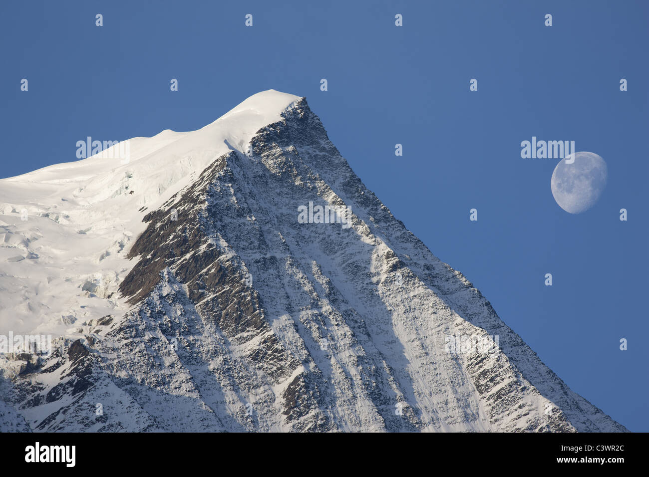 Aiguille du Gouter; ein 3786 Meter hoher Gipfel im Mont-Blanc-Massiv. Szene, die mit einem 400-mm-Objektiv aufgenommen wurde (Mond nicht hinzugefügt). Chamonix, Haute-Savoie, Frankreich. Stockfoto
