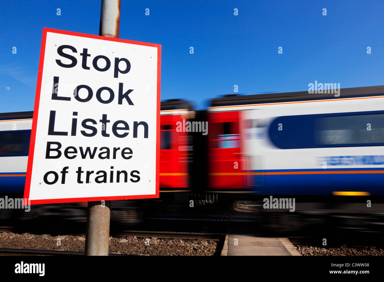 Stop look listen Vorsicht vor Züge Zeichens durch einen beschleunigten Zug passiert ein Bahnübergang Warnschild England GB UK Europa Stockfoto