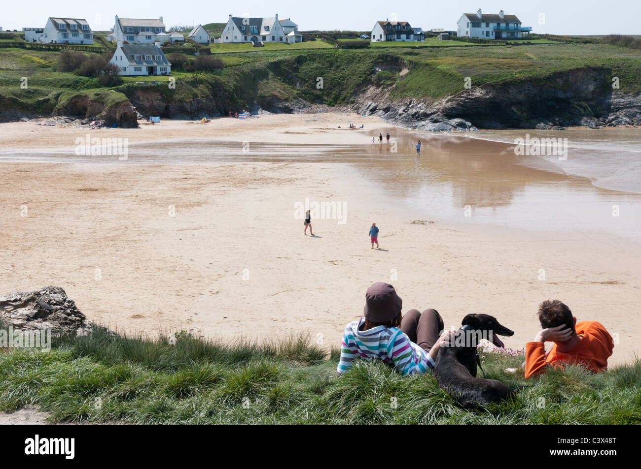 Zwei Personen und ihren Hund auf den niedrigen Klippen hinter der blauen Flagge ausgezeichneten Strand an der Treyarnon Bucht in der Nähe von Padstow, Cornwall Stockfoto