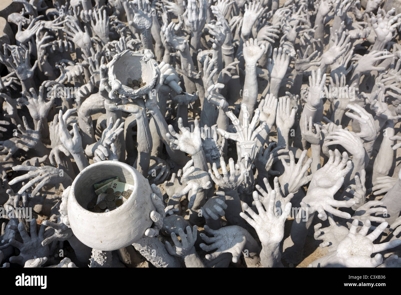 moderne Skulptur der erhöhten menschlichen Fragen für wohltätige Zwecke, einschließlich Schüssel mit Geld, Tempel Wat Rong Khun, Chiang Rai, thailand Stockfoto