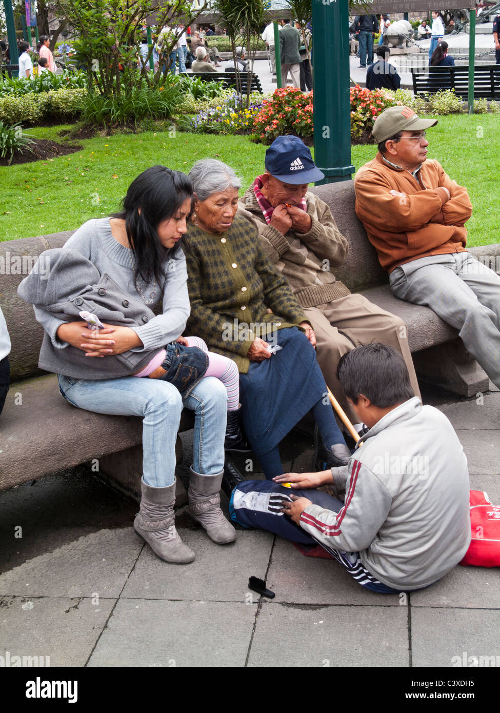 Shoe Shine Boy und Leute sitzen auf einer Bank Plaza Grande, Centro Historico, Quito, Ecuador Stockfoto