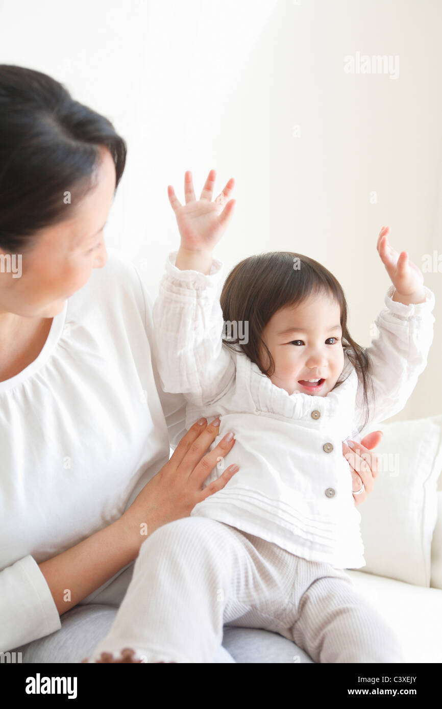 Aufgeregt Baby Mädchen auf Mutters Schoß Stockfoto