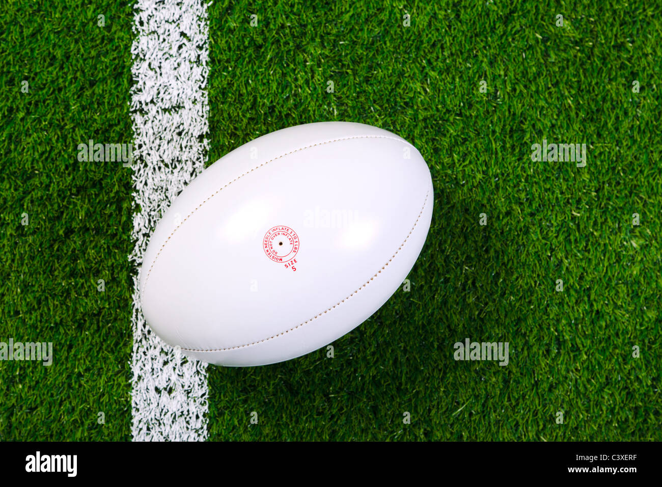 Foto von einem Rugby-Ball auf einer Wiese neben der weißen Linie, von oben geschossen. Stockfoto