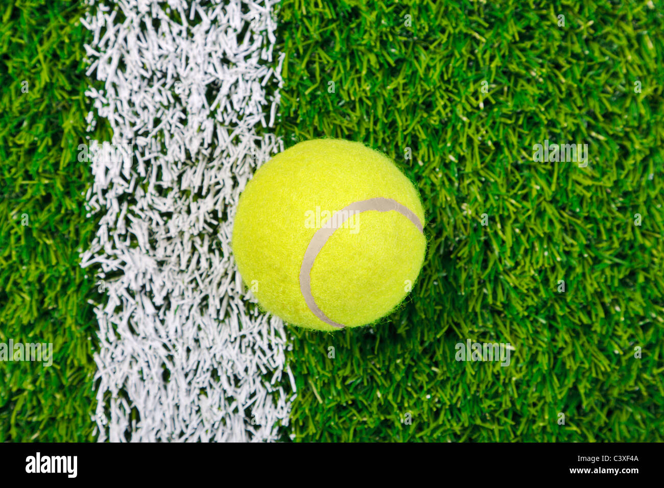 Foto von einem Tennisball auf einer Wiese neben der weißen Linie, von oben geschossen. Stockfoto