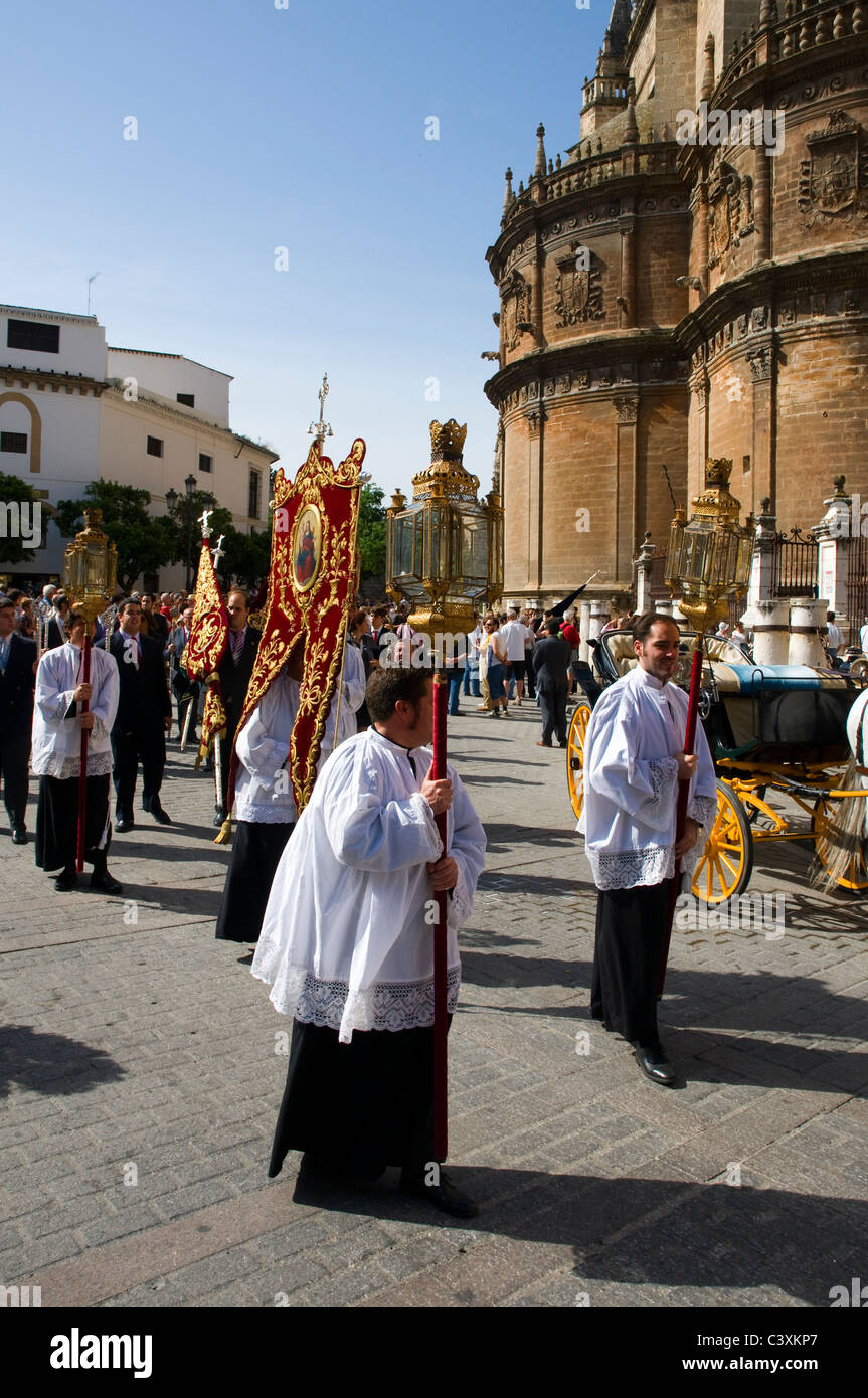 Eine religiöse Prozession, die ausgehend von der Kathedrale in Sevilla, Spanien. Priester tragen Lampen mit Kerzen und Fahnen. Stockfoto