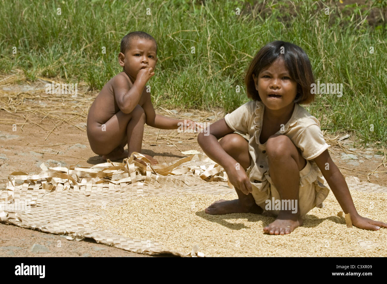 Kinder hocken neben der Straße südlich von Steng Treng. Stockfoto