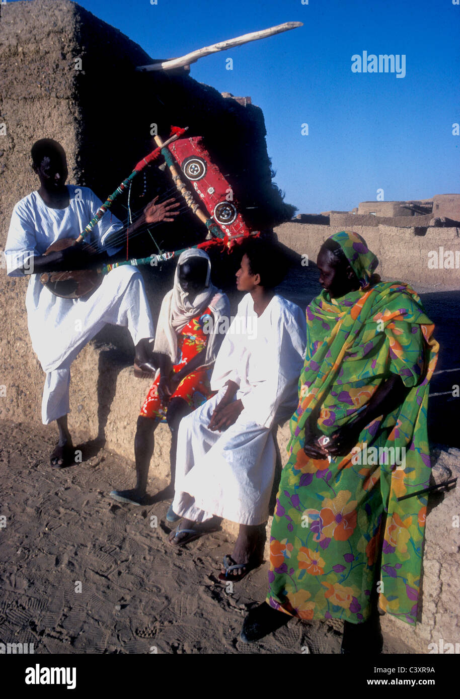 Mann spielt eine sechs Zeichenfolge Tambora mit Kindern und Frau in nationalen Kleid Sudan Stockfoto