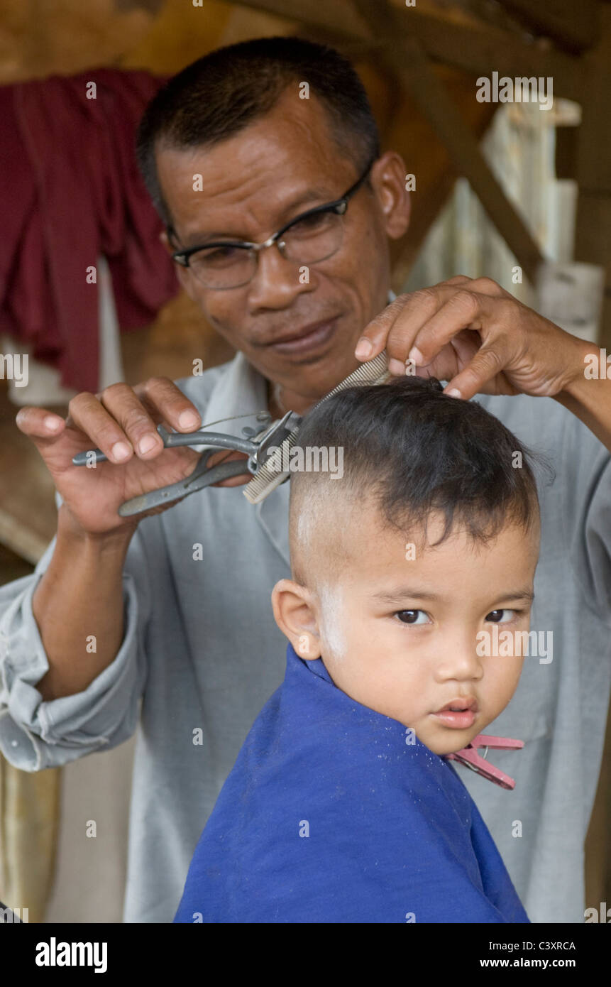 Ein Kind wird seine Haare bei einem am Straßenrand Friseur schneiden. Stockfoto