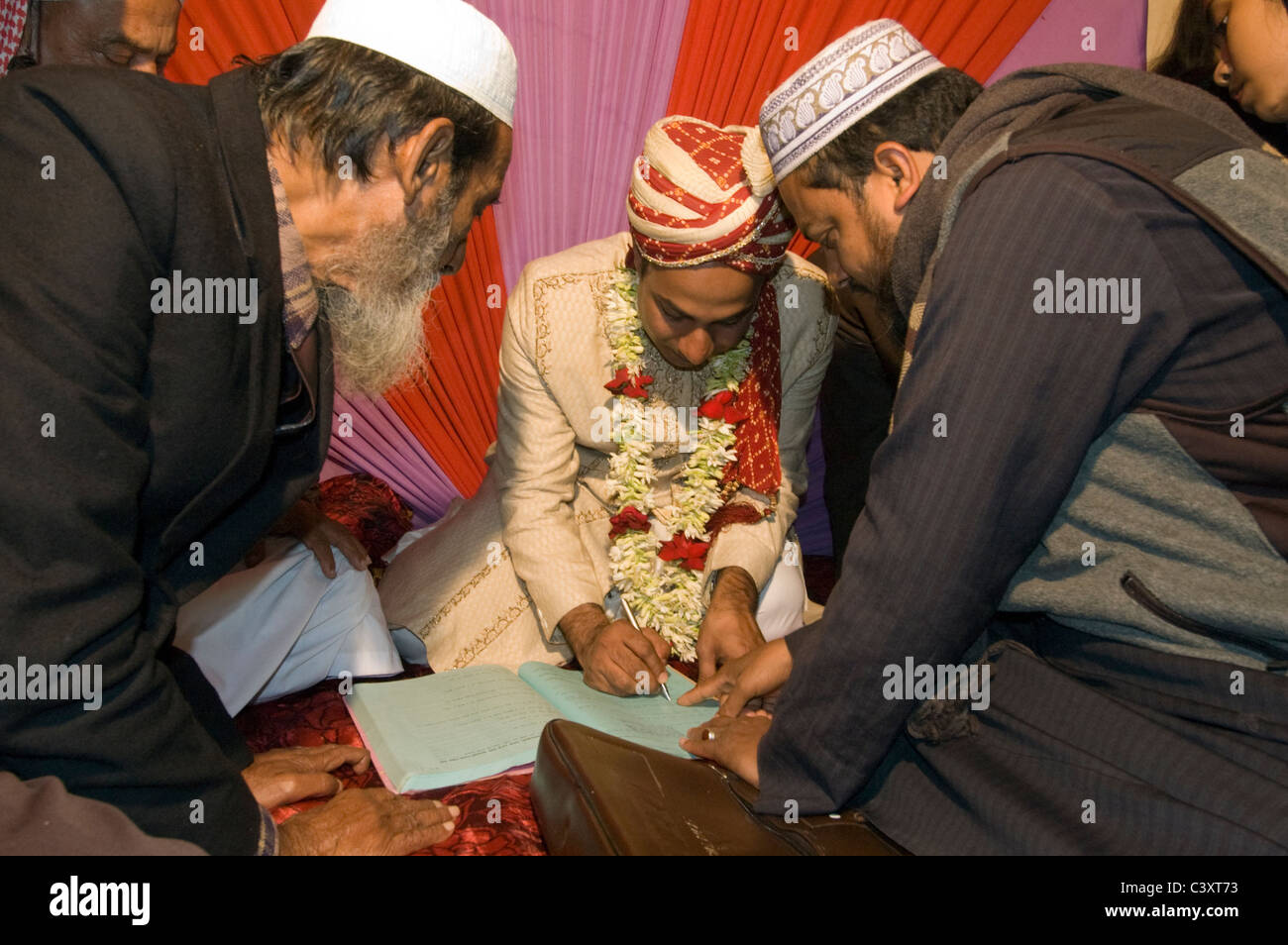 Der Bräutigam unterschreibt den Ehevertrag, bevor sein Vater und die Bräute am Tag seiner Hochzeit Vater. Stockfoto