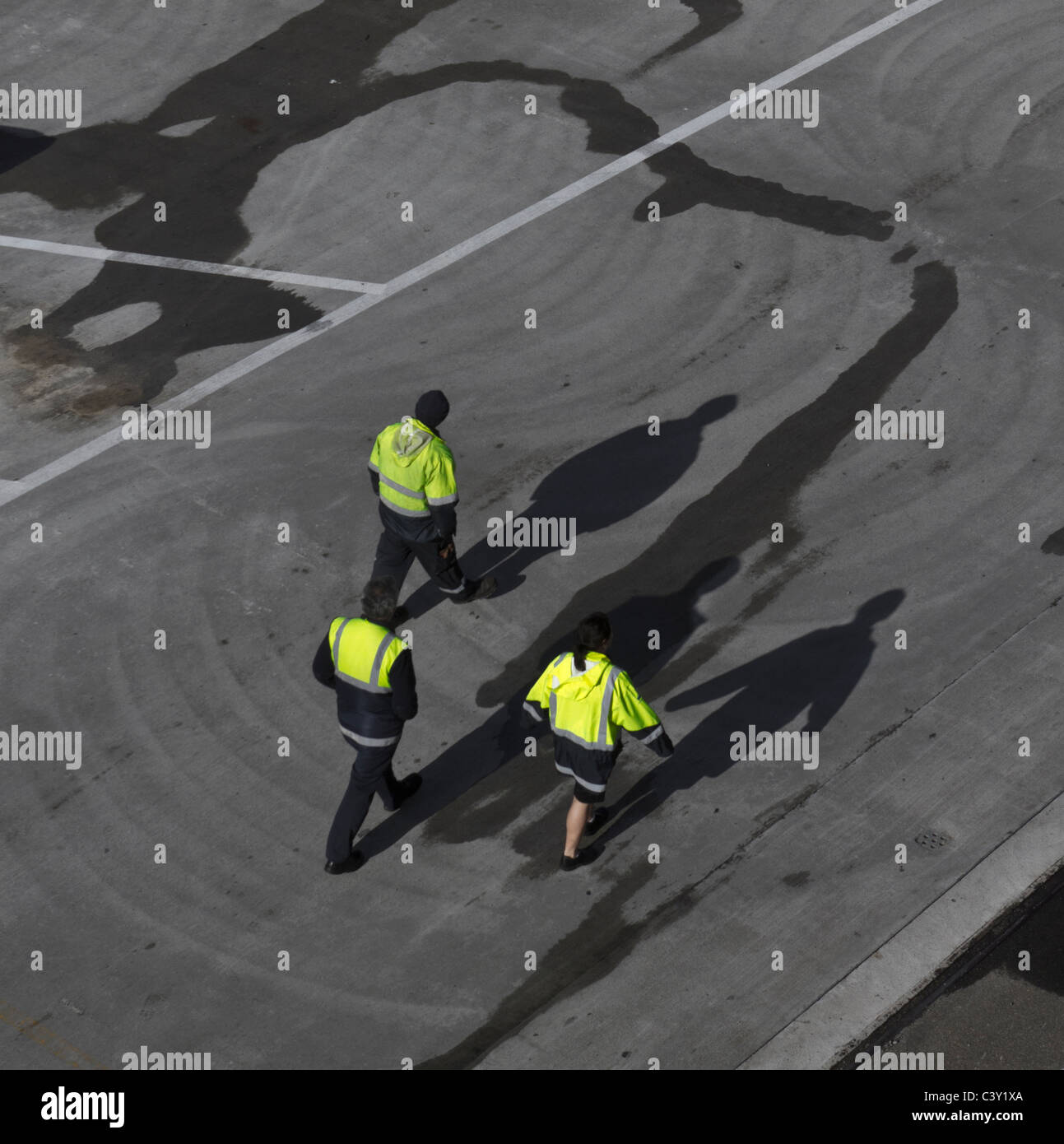 Drei Arbeiter auf der Anklagebank in Wellington, NZ, fluoreszierenden Jacke mit langen Schatten tragen, Asphalt entlang Stockfoto