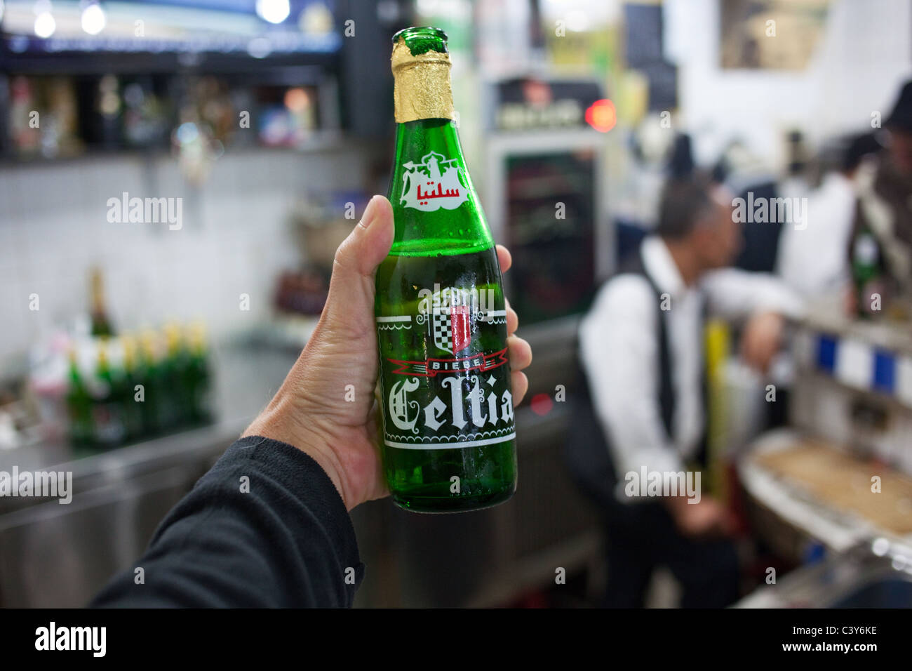 Eine Flasche eines beliebten tunesischen Bier Celtia halten in einer Hand in einer Bar in Sfax, Tunesien. Stockfoto