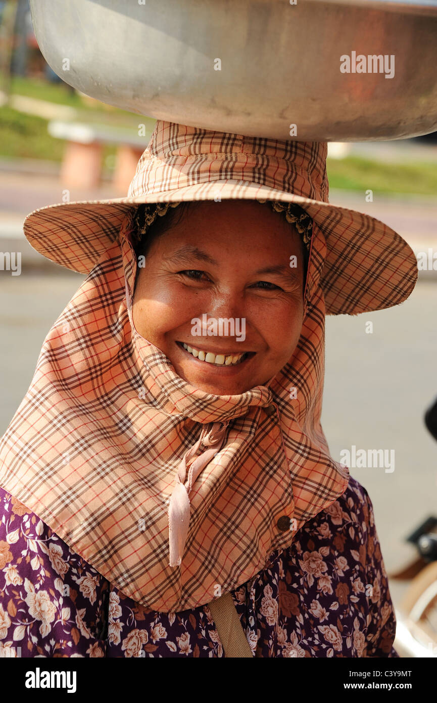 Kambodscha-Frau mit großen Behälter auf ihrem Kopf lächelnd. Stockfoto