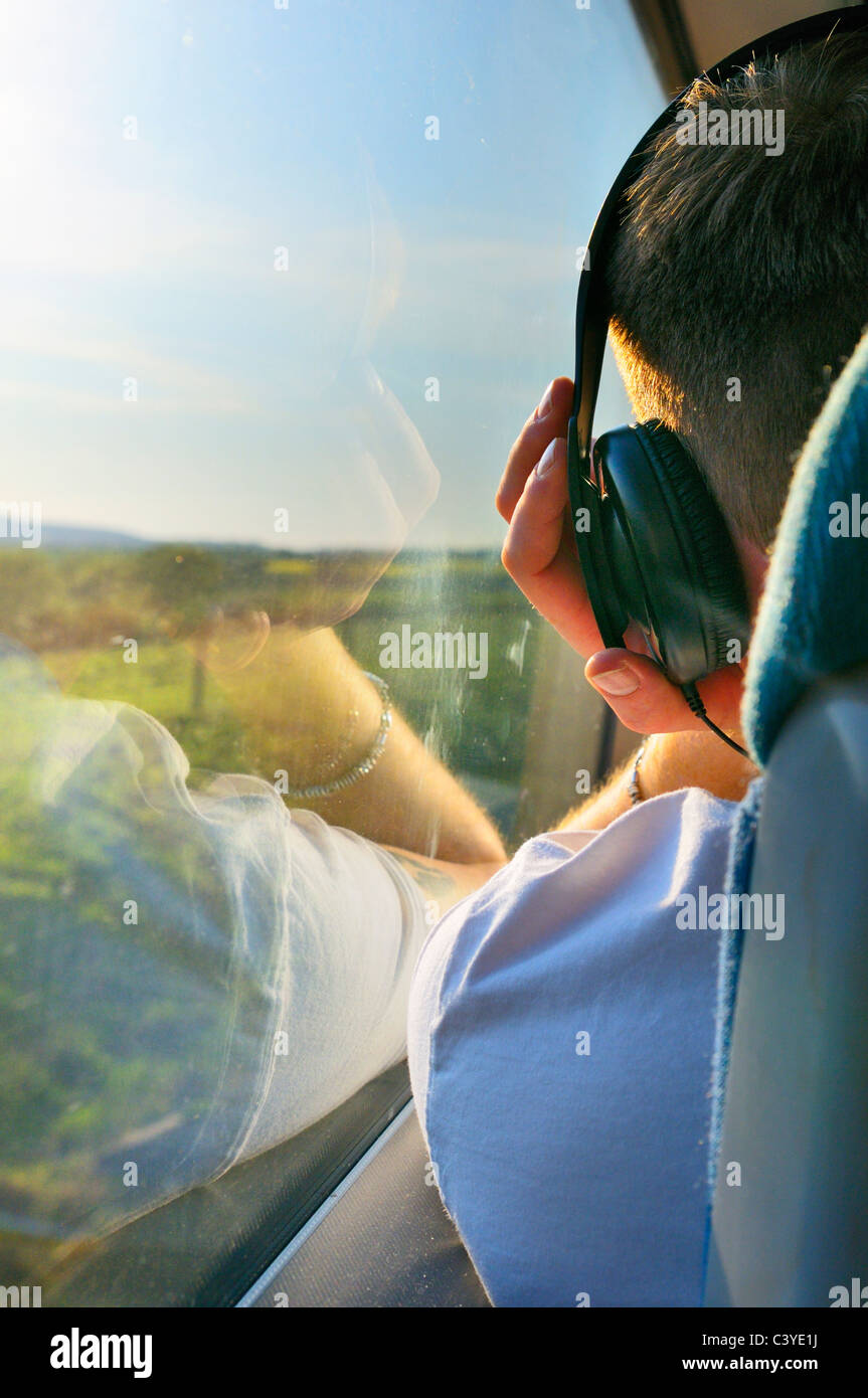 Junger Mann Musikhören mit Kopfhörer auf einer Zugfahrt Stockfoto