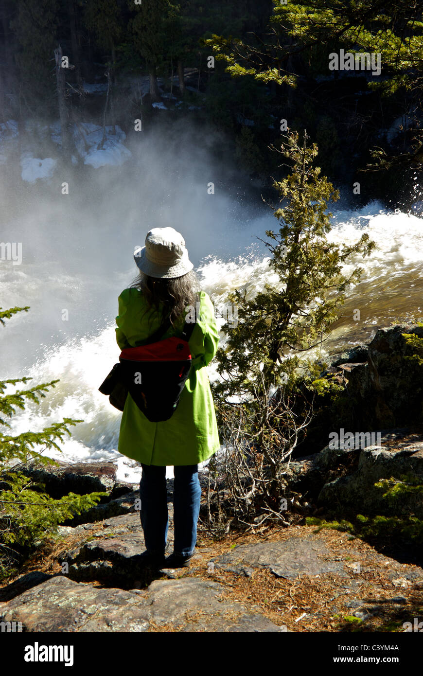 Weibliche Wanderer betrachten wütende Rivière-du-Loup während volle Frühjahr Hochwasser Kaskadierung über Le Rutsche Aux zittert Wasserfall Stockfoto