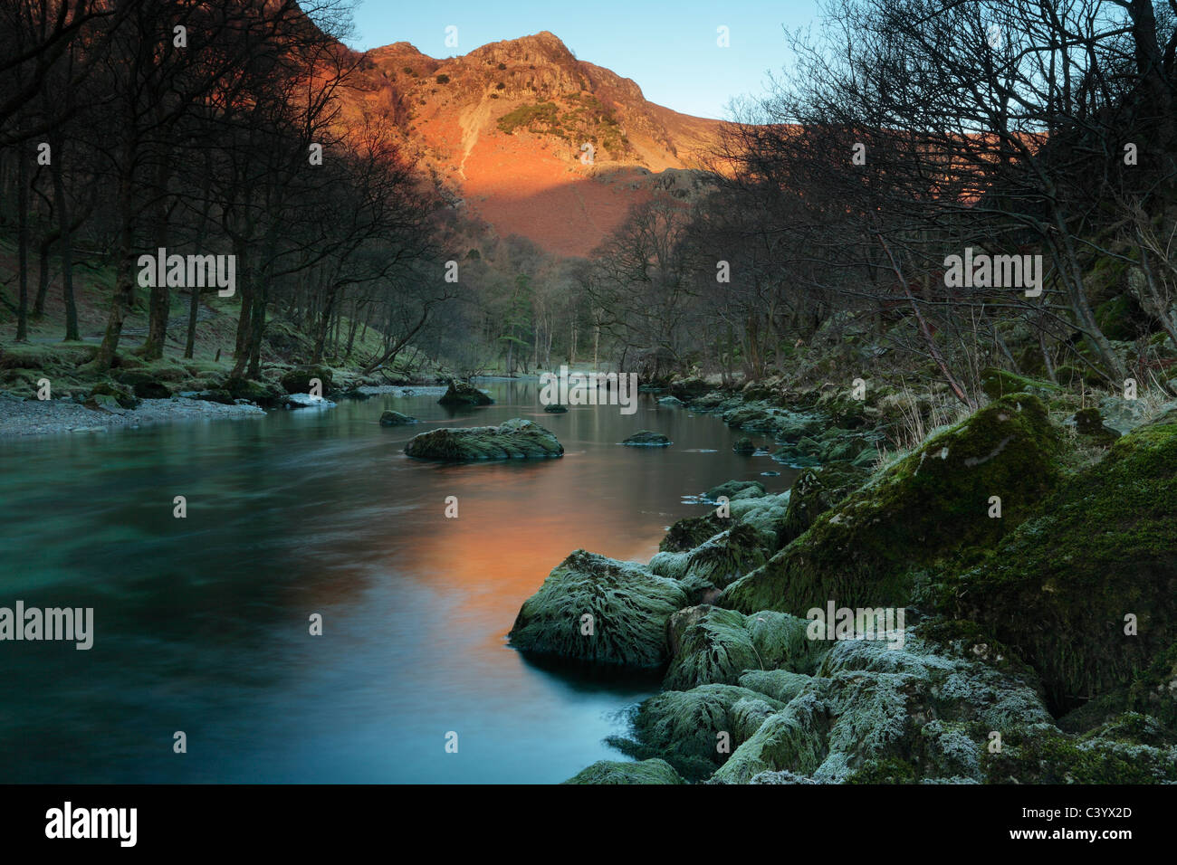 Alpenglühen auf hohen Klippen spiegelt sich in den Fluss Derwent, wie in der Nähe von Rosthwaite in den Lake District in England gesehen Stockfoto