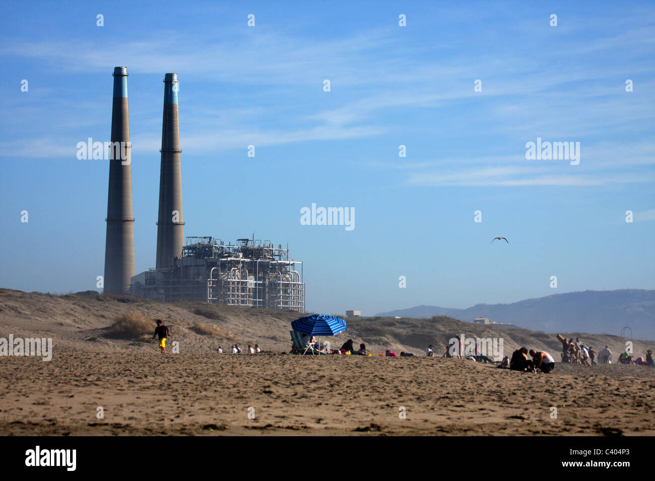 Menschen auf Moss Landing State Beach mit Moss Landing Kraftwerk im Hintergrund Stockfoto